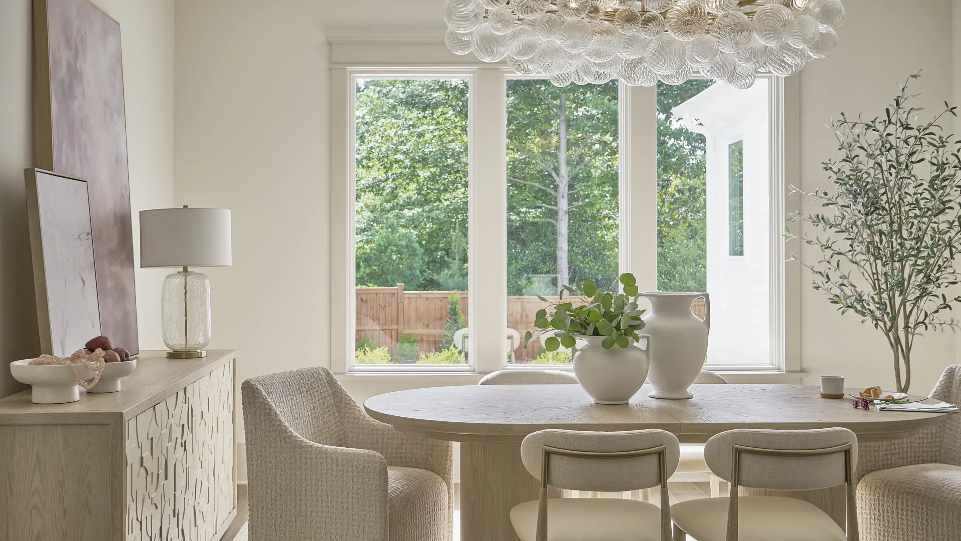 Elegant dining room with large window, contemporary chandelier, and neutral decor.